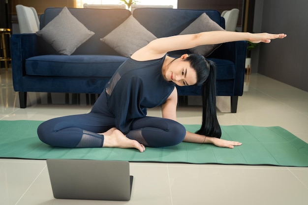 Aziatische vrouw traint thuis online aan lichaamsbeweging