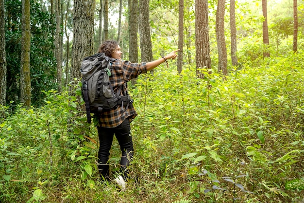 Aziatische vrouw trekt in het bos terwijl ze naar iets wijst