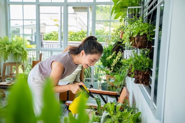 Aziatische vrouw Tuinman Sproeien van water op de plant in de tuin om thuis te ontspannen.