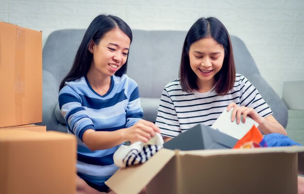 Aziatische vrouw twee die verschillende dingen van het verplaatsen van nieuw huis uitpakken.