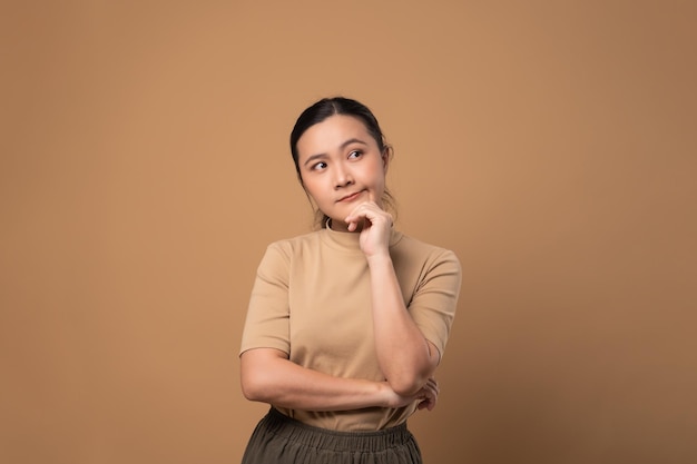 Aziatische vrouw verveeld en geïrriteerd voelt zich verward staan geïsoleerd op beige achtergrond