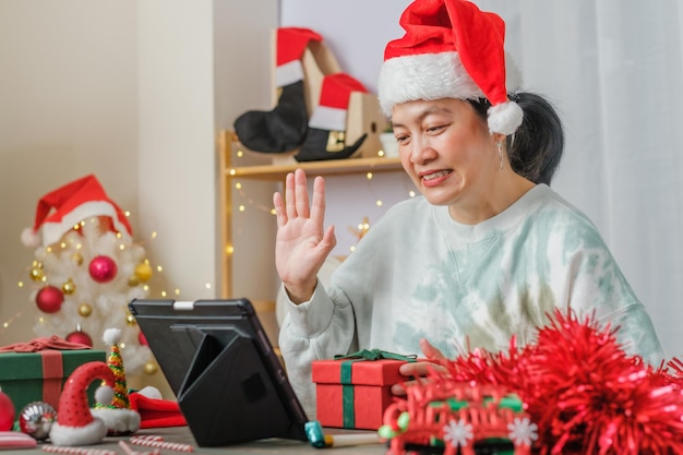 Aziatische vrouw viert nieuwjaar en kerstfeest met vrienden voor tabletvideogesprekken thuis