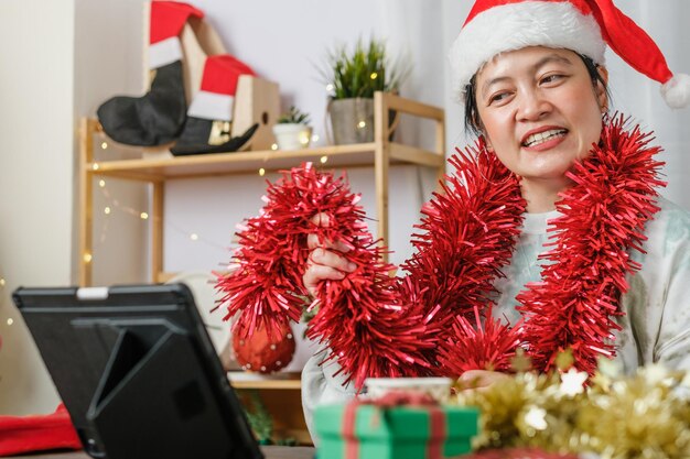 Aziatische vrouw viert nieuwjaar en kerstfeest met vrienden voor tabletvideogesprekken thuis