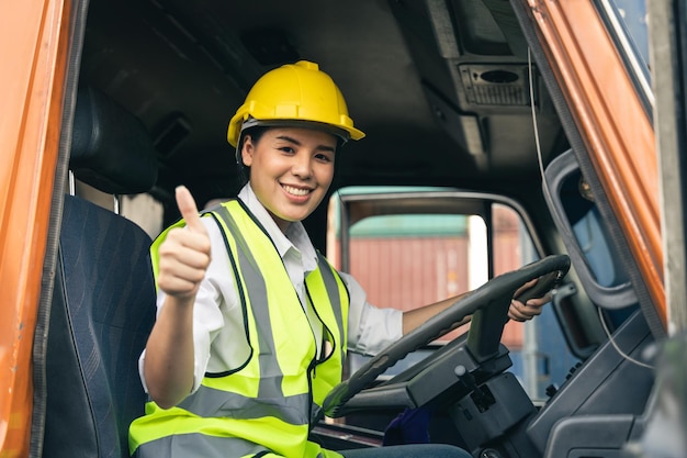 Aziatische vrouw vrachtwagenchauffeur zittend in de cabine van de vrachtwagen kijken naar de camera.