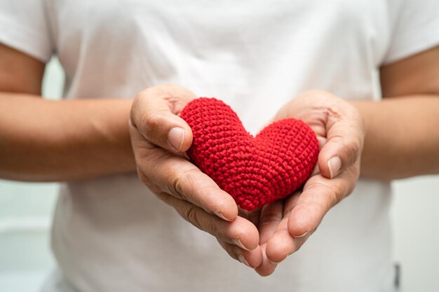 Aziatische vrouw vrijwilliger met een rood hart donatie liefdadigheidsvertrouwensverzekeringsconcept