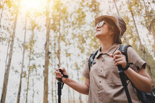 Aziatische vrouw wandelpad en trekking in het bos alleen. Reizen en buitenactiviteiten. Ontspan en recreatie in de herfstvakantie.