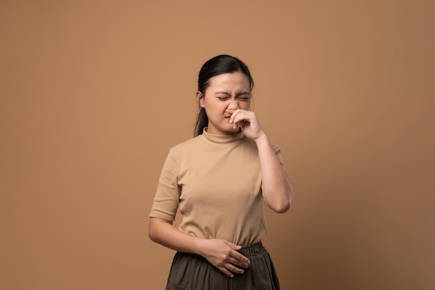 Aziatische vrouw was ziek met een zere keel, hoestend, niezend en geïsoleerd op een beige achtergrond