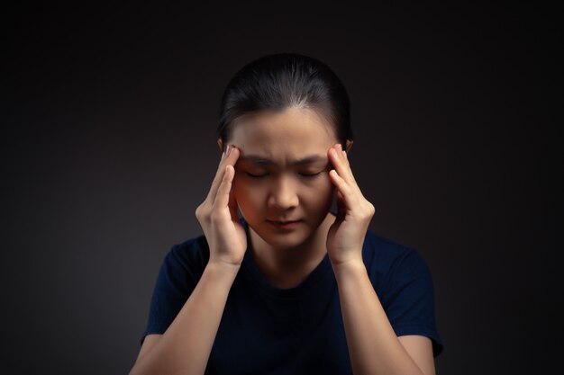 Aziatische vrouw was ziek met hoofdpijn aanraken van haar hoofd staande geïsoleerd op de achtergrond.