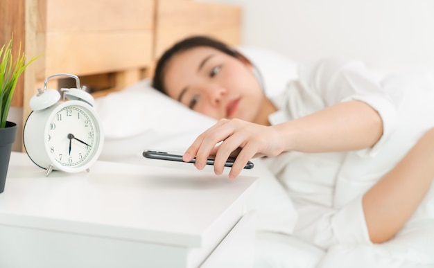 Aziatische vrouw werd net 's ochtends wakker en op het bed pakte de telefoon om haar sociale media te controleren.