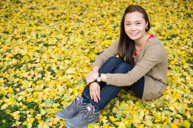 Aziatische vrouw zit op Ginkgo bladeren achtergrond in de tuin.