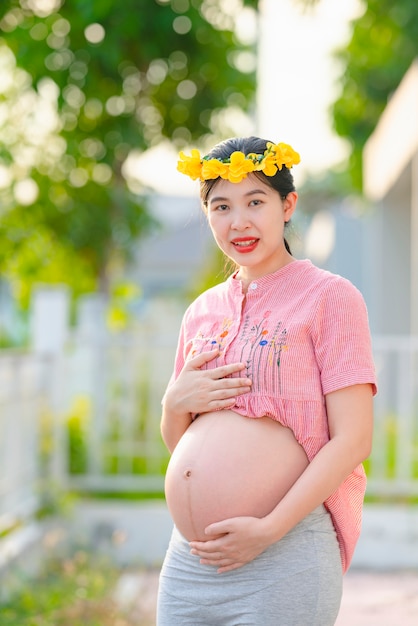 Aziatische vrouw, zwangere vrouw die een roze kleed draagt, die gelukkig glimlacht