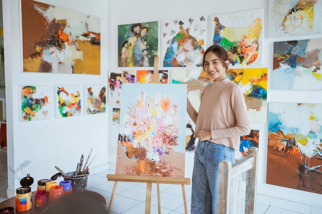 Aziatische vrouwelijke artiest die op canvas schildert en enkele kunstprojecten doet in haar studioworkshop