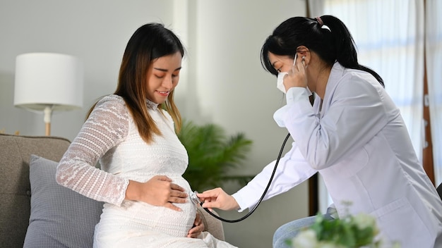 Aziatische vrouwelijke arts of verloskundige die de hartslag van de baby door haar stethoscoop luistert