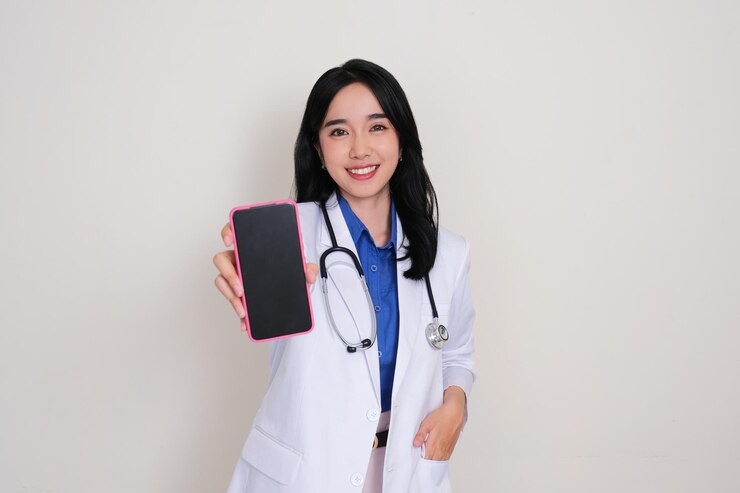 Foto aziatische vrouwelijke dokter glimlacht gelukkig terwijl ze een leeg scherm van een mobiele telefoon toont