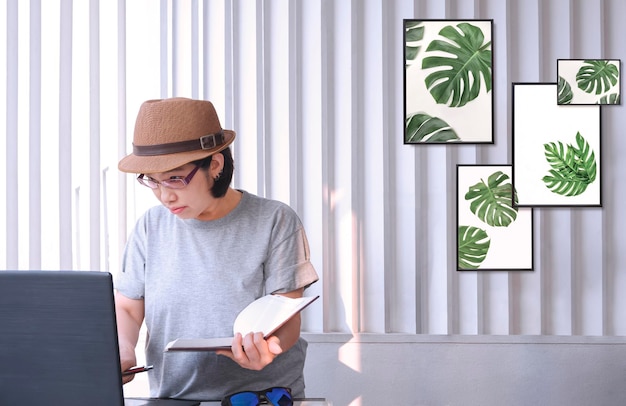 Aziatische vrouwelijke hipster-ontwerper in vintage kleding met behulp van laptopcomputer tijdens het werken in het kantoor aan huis