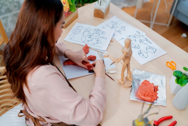 Aziatische vrouwelijke kunstenaar een arttoys kleisculptuur brengt een weekenddag door voor haar hobby klei scuplt definieert de vorm van het gezicht op de juiste manier terwijl ze het kleistandbeeld thuis maakt studio casual levensstijl thuis