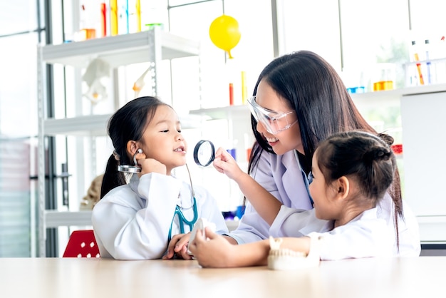 Aziatische vrouwelijke leraar en 2 studente, die een wit doktersuniform in de wetenschap dragen