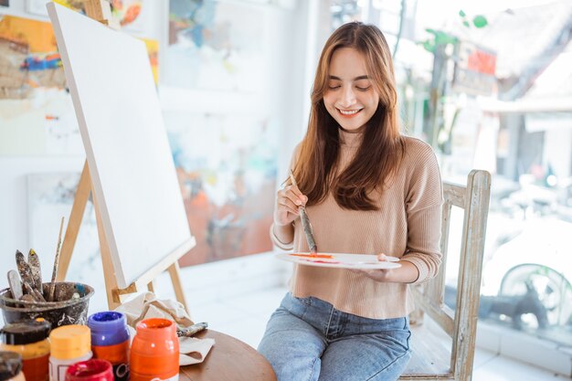 Aziatische vrouwelijke schilder schilderen op canvas in haar atelier