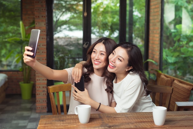 Aziatische vrouwelijke vrienden knuffelen en maken samen een selfie-foto