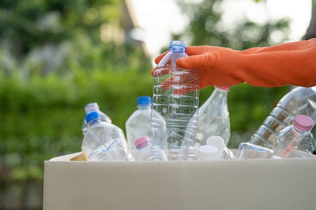 Aziatische vrouwelijke vrijwilliger draagt plastic waterflessen in de vuilnisbak