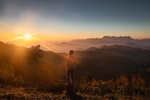 Aziatische vrouwelijke wandelaar staat en kijkt 's ochtends naar de zonsopgang op de bergtop in het nationale park Doi Kham Fah, Chiang Mai Thailand