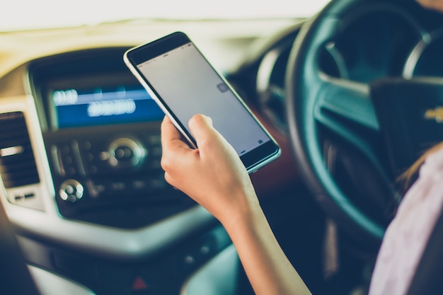 Aziatische vrouwen besturen auto&#39;s en gebruiken een smartphone op de weg.