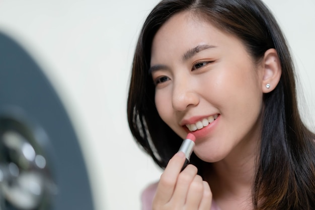 Aziatische vrouwen brengen lippenstift op hun lippen aan.