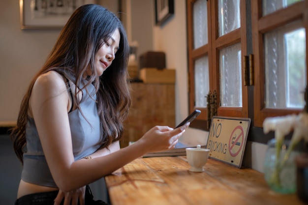 Foto aziatische vrouwen controleren de informatie van de celtelefoon in koffiewinkel