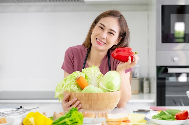 Aziatische vrouwen die biologische salade koken, eten gezond thuis in de keuken