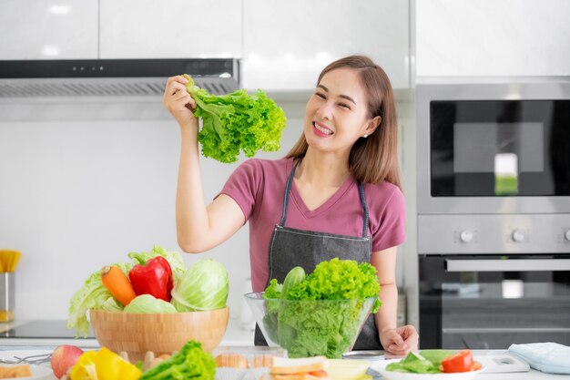 Aziatische vrouwen die biologische salade koken, eten gezond thuis in de keuken