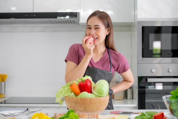 Aziatische vrouwen die in de keuken glimlachen, groentesalade koken, eten gezond