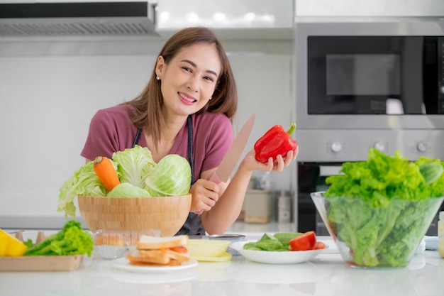 Aziatische vrouwen die in de keuken glimlachen, groentesalade koken, eten gezond