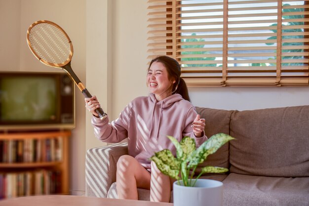 Aziatische vrouwen die leuke het racketzitting van de holdingstennis in ruimte gelukkige glimlach zitten