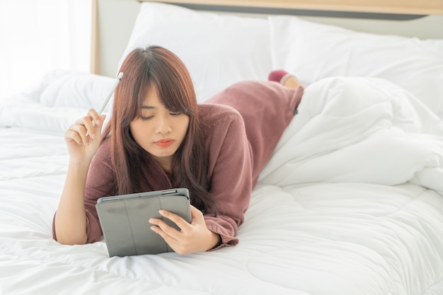 Aziatische vrouwen die met tablet aan bed werken