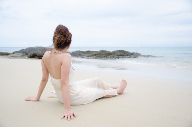 Aziatische vrouwen die op overzees strand zitten