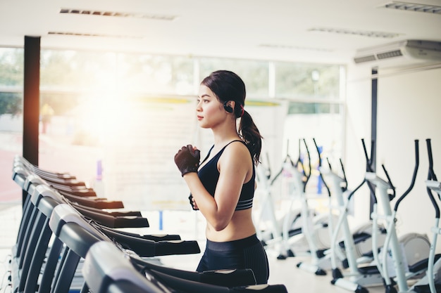 Aziatische vrouwen die sportschoenen bij de gymnastiek en de vrouw in werking stellen hebben jogging op de tredmolen