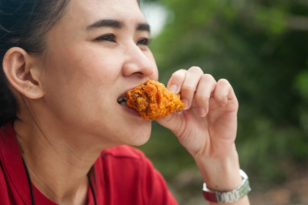 Aziatische vrouwen eten kippenvleugel zittend op tafel