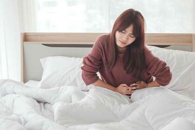 Aziatische vrouwen hebben buikpijn en ongemak op het bed.