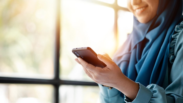 Aziatische vrouwen in hijab gebruiken de administratie en operaties van de mobiele telefoon van de jonge, slimme werkende vrouwen het managementconcept drijft het bedrijf van vrouwelijke leiders om te groeien