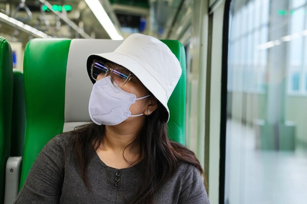 Aziatische vrouwen met een medisch masker die reizen met een openbare trein