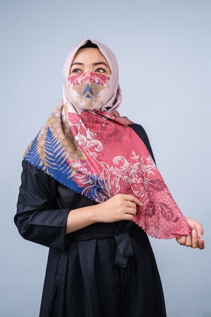 Aziatische vrouwen met hijab en modieuze gezichtsmasker poseren kijken naar de camera tegen een grijze achtergrond