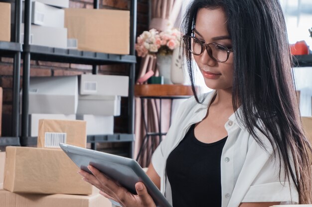 Aziatische vrouwen online verkoper die tablet gebruiken