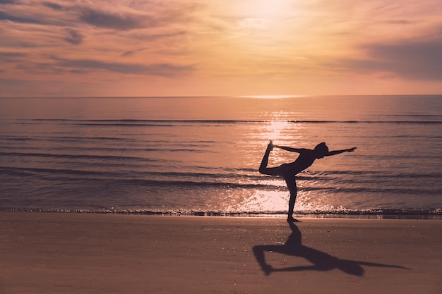 Foto aziatische vrouwen spelen yoga op een zandstrand bij de achtergrond van de zee in de ochtend