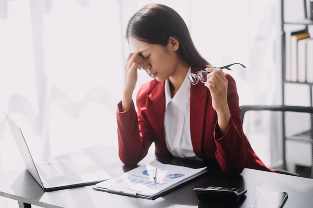 Aziatische vrouwen zijn gestrest tijdens het werken op een laptop Vermoeide aziatische zakenvrouw met hoofdpijn op kantoor voelt zich ziek op het werk kopieer ruimte