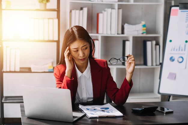 Aziatische vrouwen zijn gestrest tijdens het werken op een laptop Vermoeide aziatische zakenvrouw met hoofdpijn op kantoor voelt zich ziek op het werk kopieer ruimte