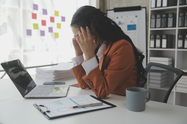 Aziatische vrouwen zijn gestrest tijdens het werken op een laptop Vermoeide Aziatische zakenvrouw met hoofdpijn op kantoor, voelt zich ziek op het werk, kopieer ruimte