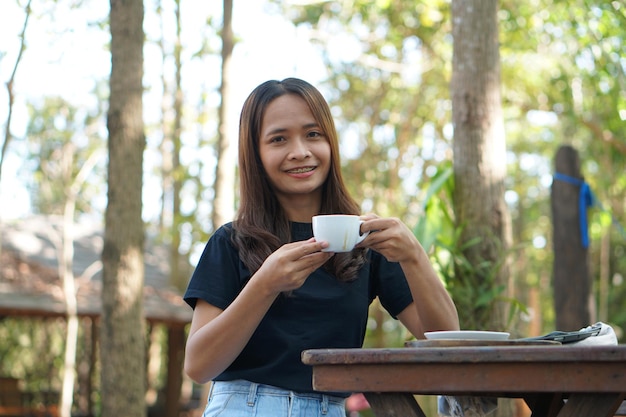 Aziatische vrouwen zitten en werken graag in een coffeeshop Er zijn groene bomen omgeven door de natuur