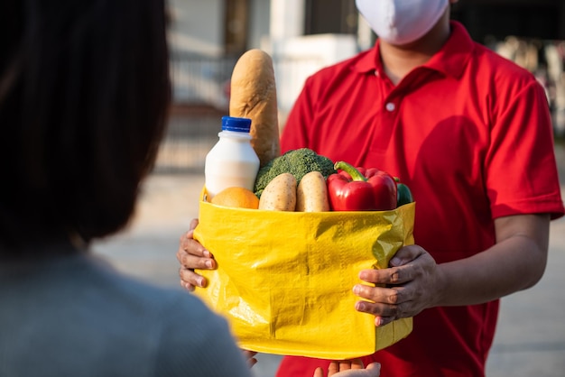 Aziatische vrouwenhand die zak voedsel, fruitgroentelevering van professionele bezorger accepteert