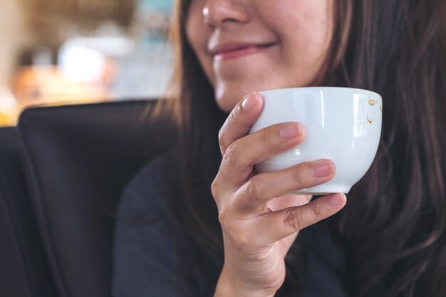 Aziatische vrouwenholding en het drinken koffie