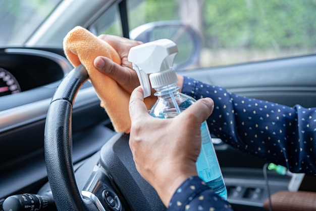 Aziatische werkende vrouw schoon in de auto door op blauwe alcoholdesinfecterende gel te drukken om het Coronavirus te beschermen